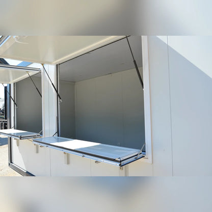 Bungalow modulaire Eurocontex – vue intérieure avec fenêtres en auvent ouvertes et comptoir rabattable aluminium